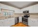 Well-lit kitchen with stainless steel appliances, white cabinets, and wood flooring at 42 Renwick Ct, Raleigh, NC 27615