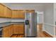 Modern kitchen with a stainless steel refrigerator, light wood cabinets, and an open view to the living room at 4622 Vendue Range Dr, Raleigh, NC 27604