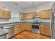 Well-lit kitchen with wooden cabinetry, stainless steel appliances, and hardwood flooring at 4622 Vendue Range Dr, Raleigh, NC 27604