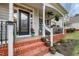 Inviting front porch with red brick steps, black door with glass, and ample space for seating at 512 Tryst Ln, Wake Forest, NC 27587