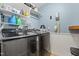 Modern laundry room with front load washer and dryer, storage shelves, and pale blue walls at 512 Tryst Ln, Wake Forest, NC 27587