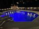 Night view of a backyard pool with a dark fence and overhead lights near deck chairs at 512 Tryst Ln, Wake Forest, NC 27587