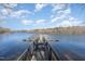 Dock surrounded by a tranquil lake with a lush green forest in the background on a partially cloudy day at 560 Waterstone Ln, Henderson, NC 27537