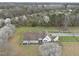 Aerial view of a home surrounded by lush, green fields and blooming trees in the background at 582 Ebenezer Church Rd, Coats, NC 27521