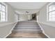 Spacious living room with neutral carpet leading to an elevated area with windows and stone fireplace at 582 Ebenezer Church Rd, Coats, NC 27521