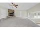Living room boasts a stone fireplace, neutral carpet, lots of natural light from multiple windows, and a ceiling fan at 582 Ebenezer Church Rd, Coats, NC 27521