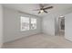Spacious carpeted bedroom with a ceiling fan, two windows, a door and a hallway at 8620 Secreto Dr, Raleigh, NC 27606