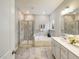 Well-lit bathroom featuring a soaking tub, glass-enclosed shower, double vanity, and neutral tile at 909 Thimbleweed Way, Wake Forest, NC 27587