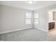 Bedroom with neutral carpet, natural light from windows, and open doorway to bathroom at 1015 Rexburg Dr, Cary, NC 27513