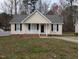 Close-up of a charming single-story home with neutral siding, black shutters, and a cozy, white picket front porch at 1032 Holly Pointe Dr, Wendell, NC 27591