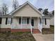 Close-up of a charming single-story home with neutral siding, black shutters, and a cozy, white picket front porch at 1032 Holly Pointe Dr, Wendell, NC 27591