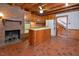 Country kitchen with brick fireplace, wood cabinets, a center island, and staircase access at 104 Parker St, Oxford, NC 27565