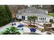Aerial view of a backyard oasis with a pool, patio, palm trees, lounge chairs, and umbrellas at 106 Woodkirk Ln, Chapel Hill, NC 27514