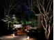 Night view of a backyard with a pool, stone patio, and ambient lighting, creating a relaxing outdoor space at 106 Woodkirk Ln, Chapel Hill, NC 27514