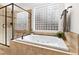 Elegant bathroom featuring a soaking tub, a glass shower, and a unique window at 106 Woodkirk Ln, Chapel Hill, NC 27514