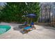 Inviting poolside lounge area with comfortable seating and an umbrella for shade, ideal for enjoying sunny days at 106 Woodkirk Ln, Chapel Hill, NC 27514