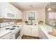 White kitchen features ample countertop space, white appliances, and a bright window for natural light at 1221 Renshaw Ct, Cary, NC 27518