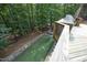 Aerial view of backyard with outdoor kitchen, artificial turf, stone fire pit, and lush, mature trees at 156 Stoney Creek Way, Chapel Hill, NC 27517