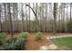 The backyard features mature trees, a path, and gravel; the landscape adds a touch of natural beauty at 156 Stoney Creek Way, Chapel Hill, NC 27517