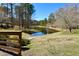 Community pond view, edged with rocks and lawn, with a wooden fence for safety at 200 Parkbranch Ln, Cary, NC 27519