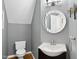 Bright powder room featuring a round mirror, stylish fixtures, and wood flooring at 200 Parkbranch Ln, Cary, NC 27519