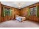 Cozy bedroom featuring wood paneling, a ceiling fan, carpet, and large windows that provide plenty of natural light at 203 Lexington Rd, Chapel Hill, NC 27516