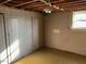 Unfinished basement featuring wooden walls and exposed ceiling beams, illuminated by a window at 2117 George Winston Rd, Oxford, NC 27565