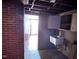 Brick-walled laundry room with utility sink and storage cabinets, leading to another room at 2117 George Winston Rd, Oxford, NC 27565