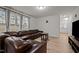 Comfortable living room featuring a leather sectional couch, ample natural light, and hardwood floors at 3015 Cypress Lagoon Ct, Durham, NC 27703