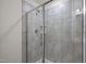 Tiled shower with frameless shower doors, shelving, and modern fixtures at 3015 Cypress Lagoon Ct, Durham, NC 27703