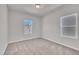 A neutral bedroom featuring carpeted floors, a ceiling light fixture, and two bright, double-paned windows at 3381 Lovage Dr, Apex, NC 27502