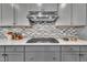 Kitchen countertop with stainless steel stove, backsplash, stainless steel hood, and gray cabinets at 3381 Lovage Dr, Apex, NC 27502