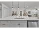 Kitchen island featuring stainless steel sink, white countertop, pendant lighting, and stainless steel dishwasher at 3381 Lovage Dr, Apex, NC 27502