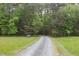 Gravel driveway leads to a property surrounded by lush greenery and mature trees at 3604 Pasture Rd, Hillsborough, NC 27278