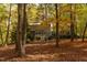 Exterior view through autumn trees highlights the home's architecture in its serene, wooded setting at 3604 Pasture Rd, Hillsborough, NC 27278