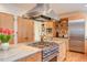 Kitchen features a stainless steel hood, stone countertops, island with stovetop, and built-in shelving at 3604 Pasture Rd, Hillsborough, NC 27278