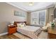 Cozy bedroom with natural light and decor, with a striped bedspread, bedside table and accent chair at 4913 Sunset Stream Dr, Fuquay Varina, NC 27526