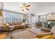Spacious living room features a large sectional sofa, ceiling fan, and ample natural light from large windows at 4913 Sunset Stream Dr, Fuquay Varina, NC 27526