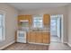 Well-lit kitchen with wood cabinets, white appliances, and a stainless steel sink. Wood-look floors throughout at 516 Craven Road, Durham, NC 27704