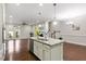 Open kitchen with granite island, pendant lights, and stainless appliances flowing into the living area at 627 Balsam Fir Dr, Cary, NC 27519