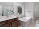 Elegant bathroom with soaking tub, double vanity, and large window overlooking wooded area at 664 The Parks Dr, Pittsboro, NC 27312