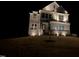 Stunning nighttime view of a two-story home with illuminated stone accents and landscaped front yard at 664 The Parks Dr, Pittsboro, NC 27312