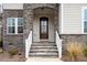 Elegant stone entryway leading to a wood front door, accented by white railings and house number at 664 The Parks Dr, Pittsboro, NC 27312