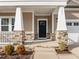 Inviting front porch with stone accents and white pillars creates a warm entry at 721 Sage Oak Ln, Holly Springs, NC 27540