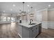 Open kitchen featuring an island with a sink, granite countertops, modern lighting, and wood-look flooring at 721 Sage Oak Ln, Holly Springs, NC 27540