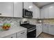 Modern kitchen featuring white cabinets, stainless steel appliances, stylish backsplash, and stone countertops at 721 Sage Oak Ln, Holly Springs, NC 27540