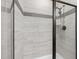 Modern shower featuring gray tiled walls with accent stripes and sleek, dark-framed glass doors at 721 Sage Oak Ln, Holly Springs, NC 27540
