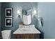 The powder room has a stylish vanity, oval mirror, sconces, and a toilet at 7217 Manor Oaks Dr, Raleigh, NC 27615