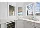 Bright wet bar with a wine cooler, sink, quartz countertops, white cabinetry, and natural light at 7217 Manor Oaks Dr, Raleigh, NC 27615