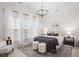 Bright main bedroom with a modern chandelier, large windows, and neutral decor at 8412 Lunar Stone Pl, Raleigh, NC 27613